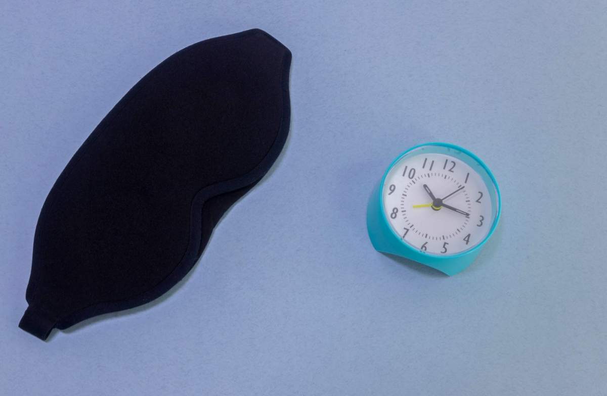 Mască de dormit pentru ochi, ceas deșteptător izolat pe un fundal roz pastelat, colorat la modă. Nu mă deranja, lasă-mă să dorm. Odihnă, noapte bună, siestă, insomnie