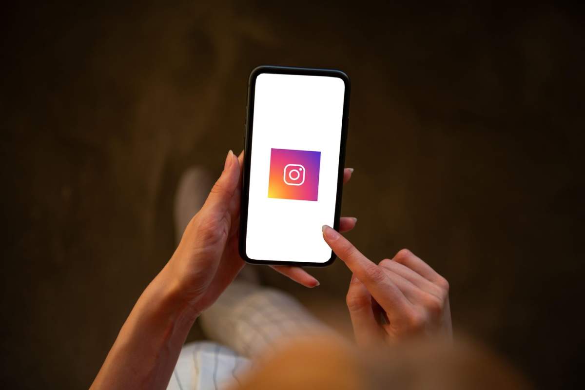 Femeie care ține un telefon mobil cu logo-ul Instagram pe ecran