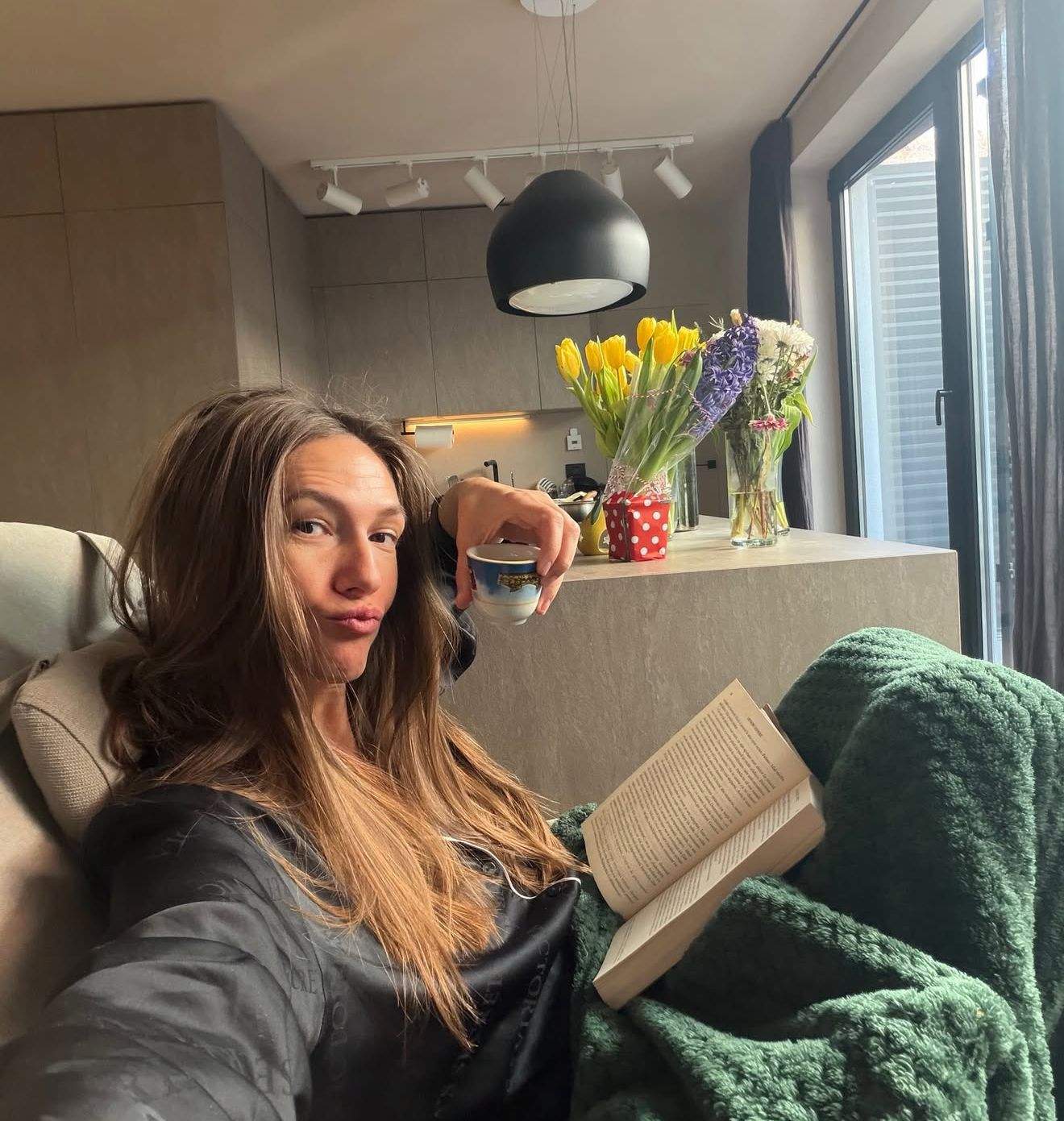 Adela Popescu citește o carte și bea cafea