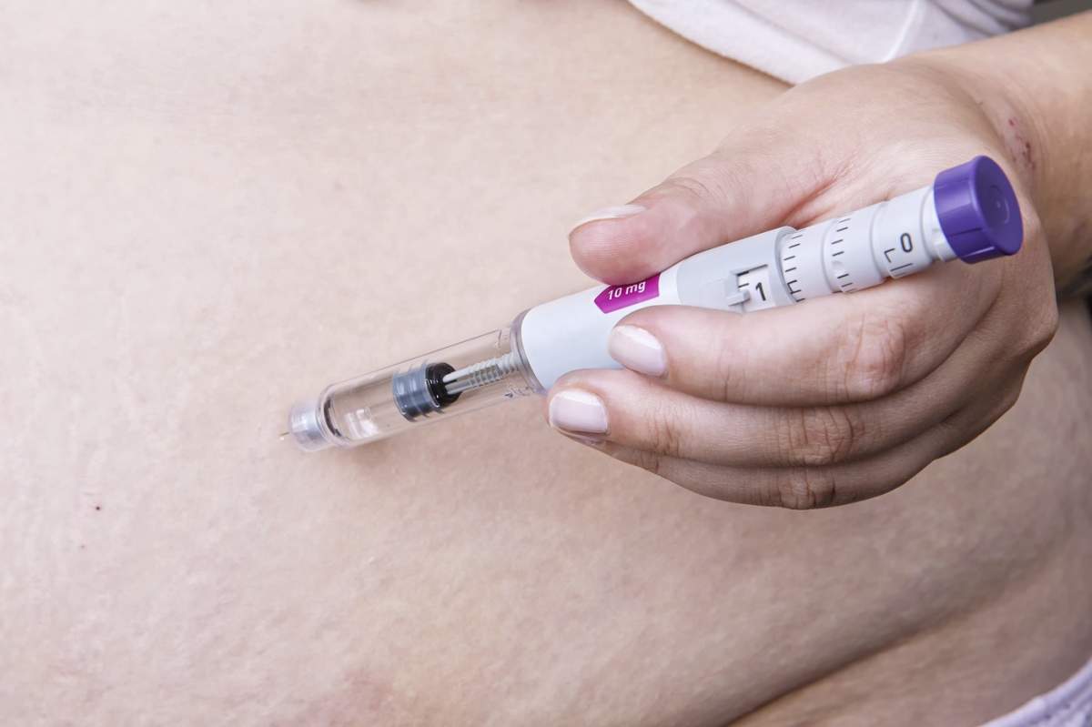 Persoană care injectează un stilou injector (pen) preumplut cu un medicament analog al peptidei-1 asemănătoare glucagonului (GLP-1), utilizat pentru gestionarea diabetului și pierderea în greutate