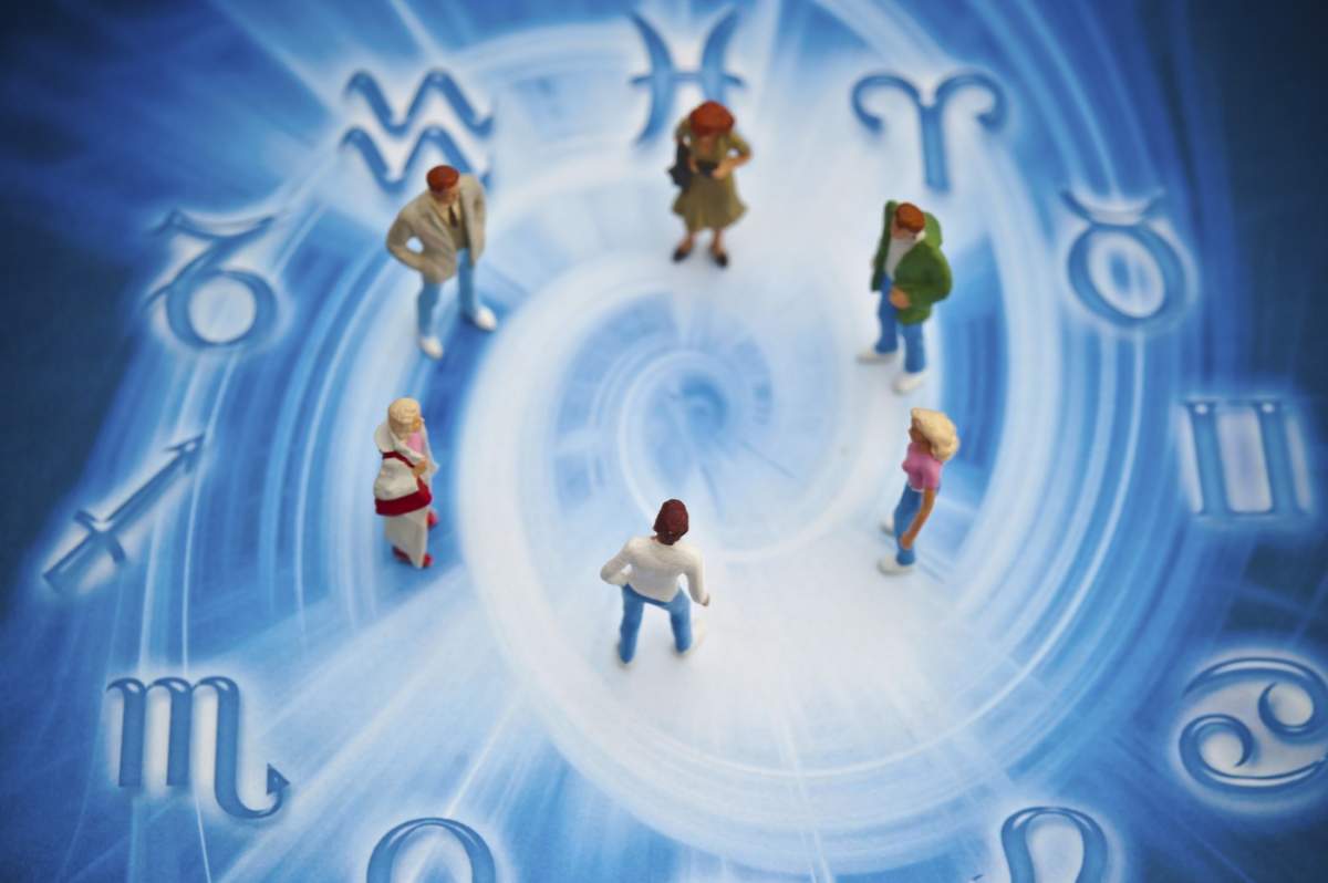 Figurine mici adunate într-un cerc înconjurate de simboluri zodiacale pe un fundal albastru