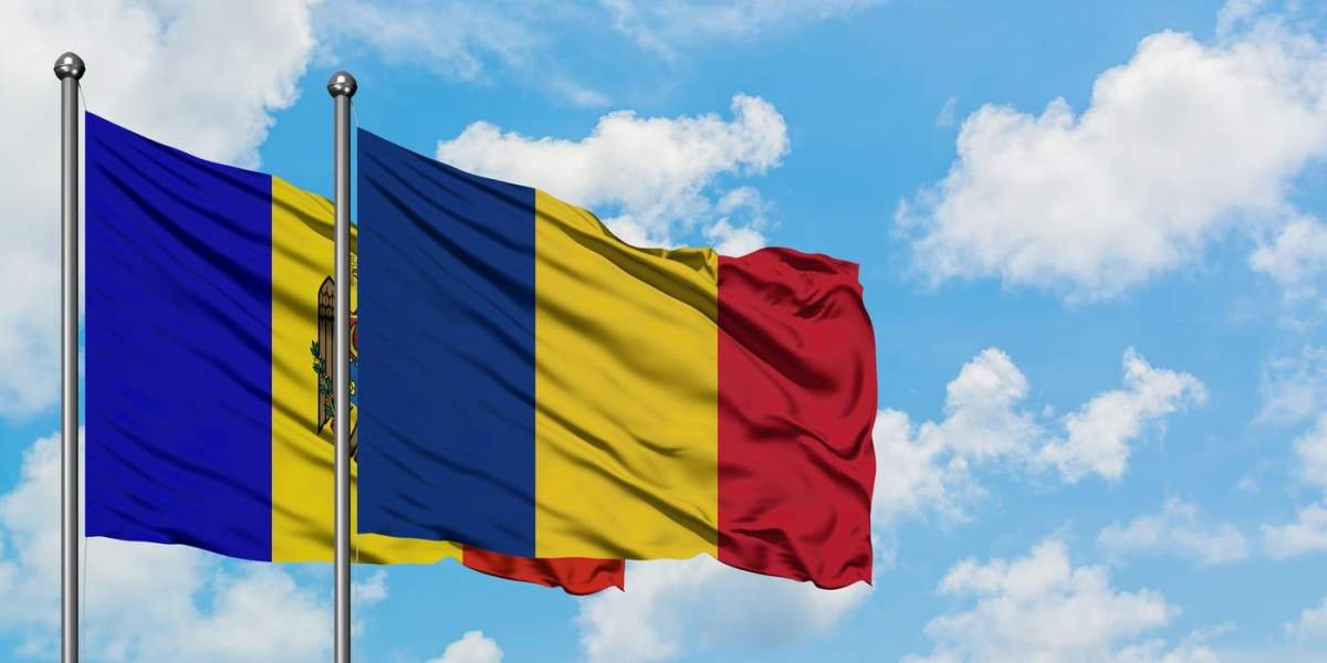 Steagurile Moldovei și României fluturând în vânt pe un cer albastru înnorat împreună
