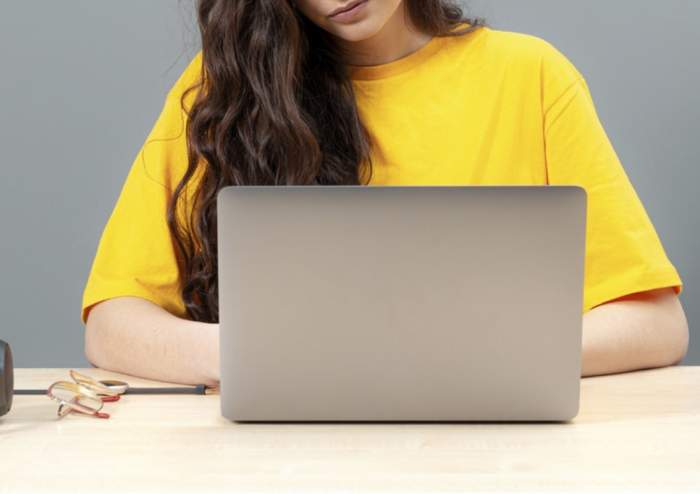 Tânără stând la masă, folosind tehnologia modernă atunci când lucrează, concept de lucru online