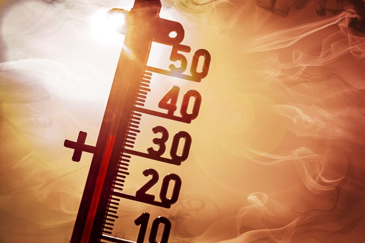 Termometrul în fața unui soare arzător arată temperaturi ridicate, val de căldură simbolic pentru fotografii, montaj foto +++ doar pentru uz editorial