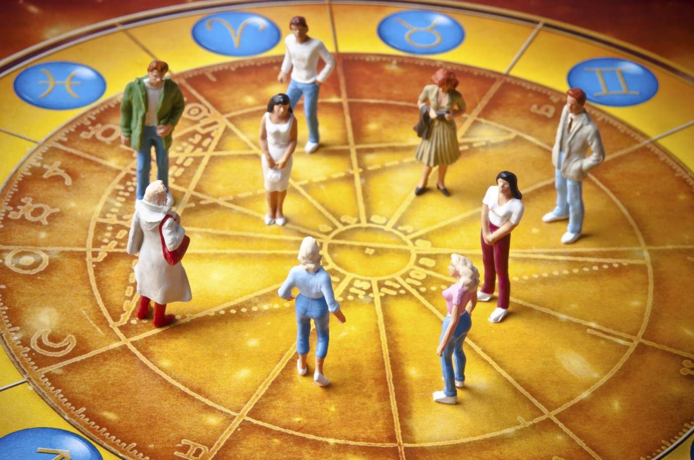 Figurine miniaturale stau pe o roată zodiacală înconjurate de semne astrologice