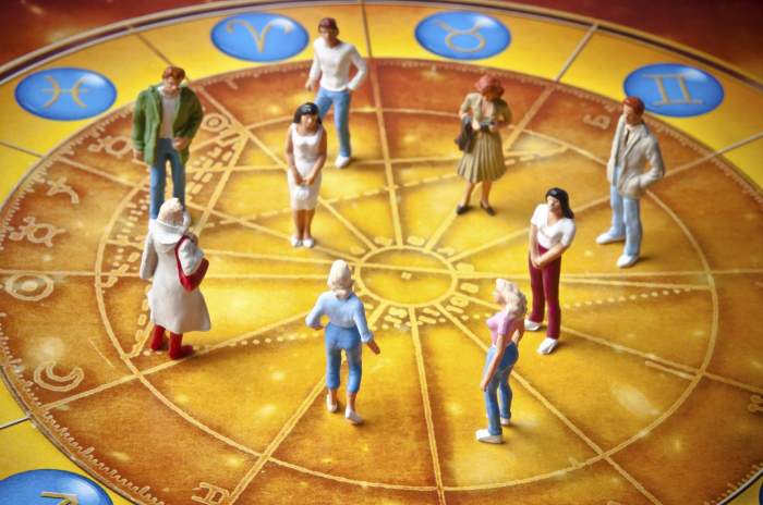 Figurine miniaturale stau pe o roată zodiacală înconjurate de semne astrologice