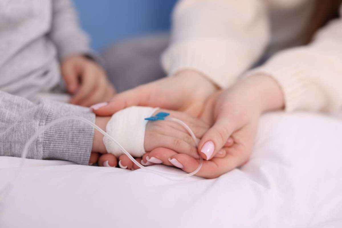 Mamă și copilul ei mic, cu perfuzie, pe patul de spital