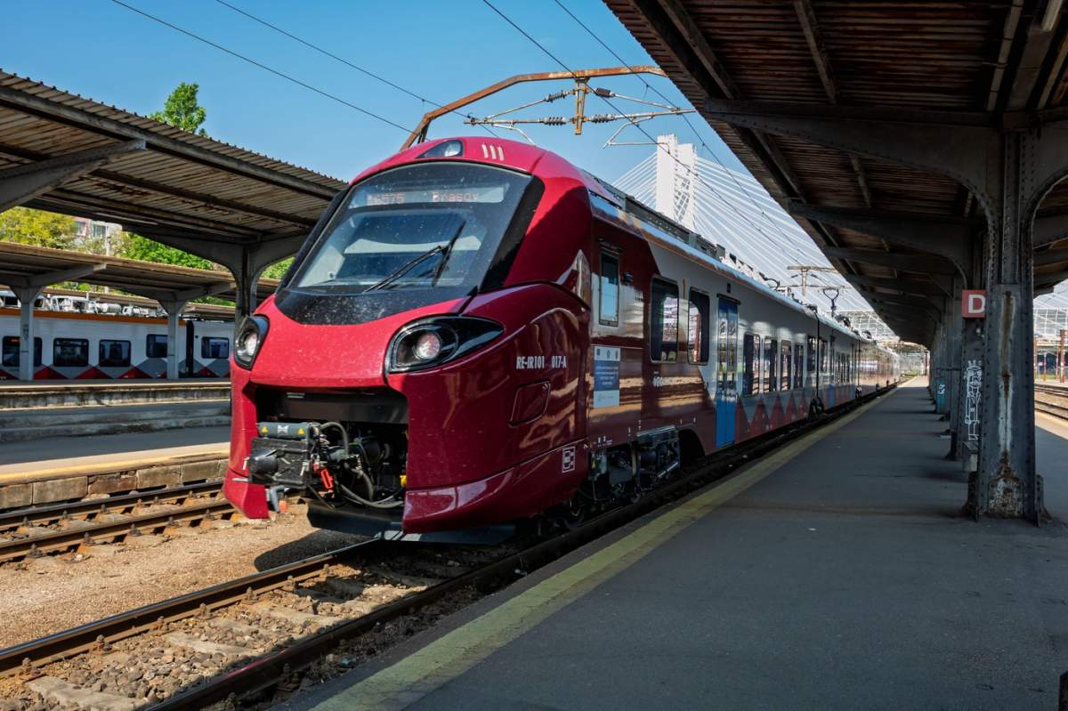Tren la peronul Gării de Nord din București, România, cu oameni care urcă și călătoresc pe calea ferată.